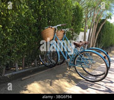 Trois vélos bleus avec paniers garés sur un trottoir ensoleillé Banque D'Images