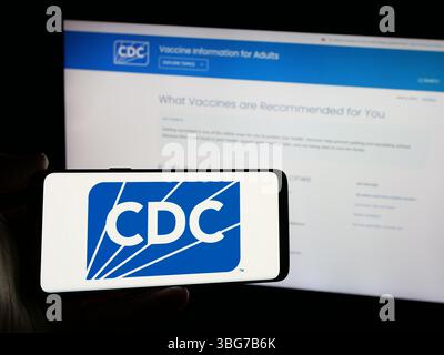 Stuttgart, Allemagne - 01 28 2025 : personne tenant un smartphone avec le logo des centres pour le contrôle et la prévention des maladies (CDC) sur l'écran devant le site Web Banque D'Images