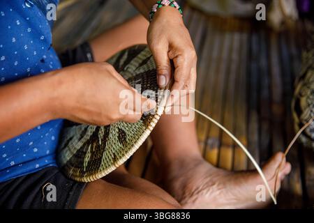 2 juin 2025 : mains d'une femme autochtone Mangyan tissant soigneusement un panier traditionnel à partir de fibres de bambou dans le village de Mangyan, Talipanan, Puerto Galera Banque D'Images