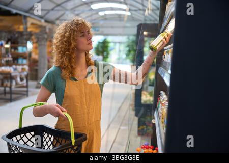 Assistant de magasin prenant la bouteille de l'étagère dans le magasin zéro déchet Banque D'Images