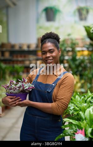 Jardinier tenant la plante en pot souriant dans la serre Banque D'Images