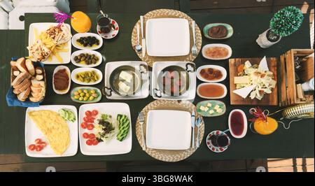 Une vue plongeante d'une table de petit déjeuner abondante avec fromages, sujuk, omelette, frites, gözleme, pain, céréales, confitures, thé et jus. Banque D'Images