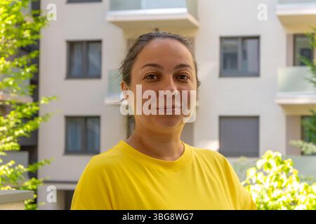 Une femme de 40-45 ans debout sur le balcon ou la terrasse d'un immeuble Banque D'Images