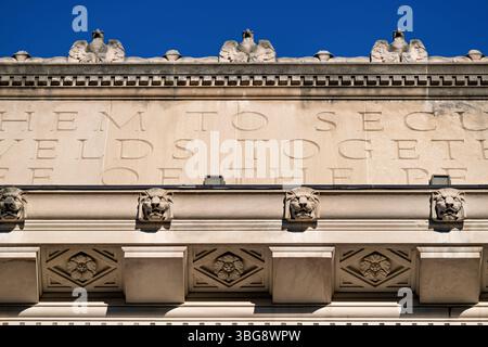 Bâtiment du Département du Commerce des États-Unis Herbert C. Hoover Building Washington DC | WASHINGTON — Des aigles sculptés, des consoles à tête de lion et une frise inscrite ornent la corniche du Herbert C. Hoover Building, le siège du Département du Commerce dans le Federal Triangle à Washington, D.C. Le sculpteur James Earle Fraser a conçu le programme sculptural extérieur du bâtiment, qui comprend ailleurs des panneaux en relief illustrant les bureaux constitutifs du département. L'architecte Louis Ayres de York & Sawyer a achevé la structure de style Renaissance Revival en 1932 en calcaire gris de l'Indiana sur une base en granit Banque D'Images