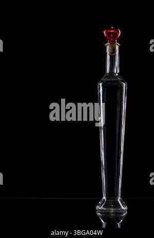 Nature morte avec une bouteille en verre vide étroite et couchée sur fond noir Banque D'Images