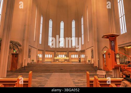 Hallgrimskirkja, avec sa flèche imposante, domine l'horizon de Reykjavik. Son design moderniste, l'intérieur de l'église dans une lumière jaune chaude Banque D'Images