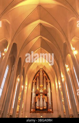 Hallgrimskirkja, avec sa flèche imposante, domine l'horizon de Reykjavik. Son design moderniste, l'intérieur de l'église dans une lumière jaune chaude Banque D'Images