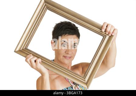 Vue du haut du corps d'une femme d'âge moyen aux cheveux noirs avec un cadre doré sur fond blanc, Berlin, Allemagne, Europe Banque D'Images