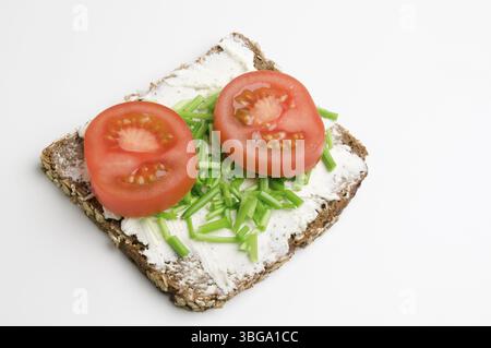 Vue surélevée d'une tranche de pain avec fromage à la crème, deux tranches de tomates et ciboulette sur fond blanc, Berlin, Allemagne, Europe Banque D'Images