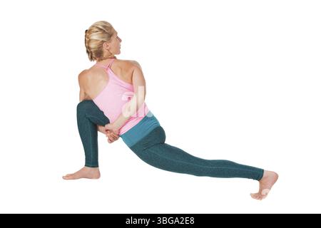 Vue latérale complète du corps d'une jeune femme isolée sur blanc en position yoga Hero Triangle (Trikonasana) Banque D'Images