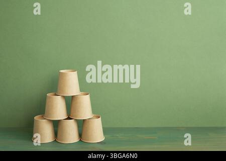 Pile pyramidale de tasse brune sur table en bois. arrière-plan vert. développement de l'entreprise concept de croissance de la réalisation Banque D'Images