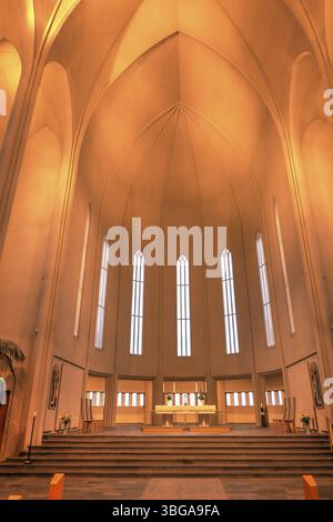 Hallgrimskirkja, avec sa flèche imposante, domine l'horizon de Reykjavik. Son design moderniste, l'intérieur de l'église dans une lumière jaune chaude Banque D'Images