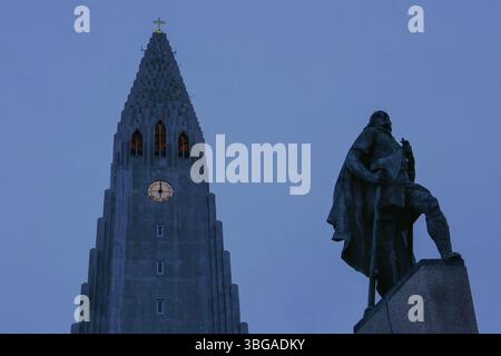 Hallgrimskirkja, avec sa flèche imposante, domine l'horizon de Reykjavik. Son design moderniste, tour de l'église avec horloge après le coucher du soleil Banque D'Images