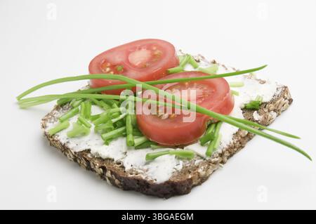Vue surélevée d'une tranche de pain avec fromage à la crème, deux tranches de tomates et ciboulette sur fond blanc, Berlin, Allemagne, Europe Banque D'Images