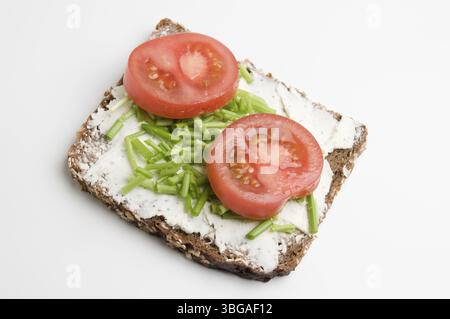 Vue surélevée d'une tranche de pain avec fromage à la crème, deux tranches de tomates et ciboulette sur fond blanc, Berlin, Allemagne, Europe Banque D'Images