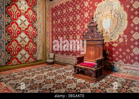 L'opulente salle du trône présente de riches tapisseries rouges et un mobilier royal orné au musée du Comte de Chambord. Banque D'Images