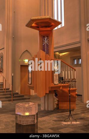 Hallgrimskirkja, avec sa flèche imposante, domine l'horizon de Reykjavik. Son design moderniste, l'intérieur de l'église dans une lumière jaune chaude Banque D'Images