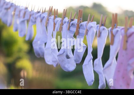 Chaussettes de bébé dans différents tons pastel suspendus à l'extérieur, reflétant les routines familiales, la douceur de vivre, le minimalisme et les soins à domicile organiques dans un environnement propre et Banque D'Images