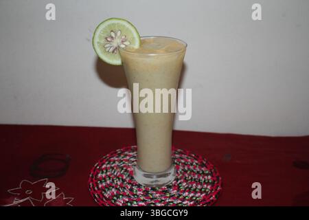 Un verre haut et élégant rempli d'un smoothie beige crémeux ou d'un milk-shake. La boisson est faite à partir de fruits, lait, yaourt, sucre, eau etc. Banque D'Images