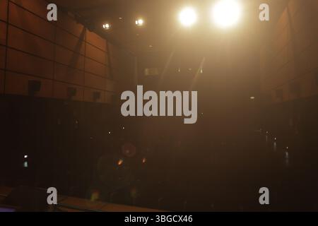 Lumières de scène lumineuses éclairant un large public dans un théâtre sombre, créant une atmosphère dramatique et captivante Banque D'Images