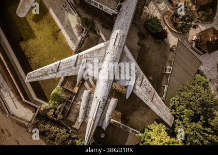 Vue aérienne d'un avion en décomposition reposant sur les terrains d'un parc d'attractions abandonné, montrant la décomposition urbaine et le déclin industriel Banque D'Images