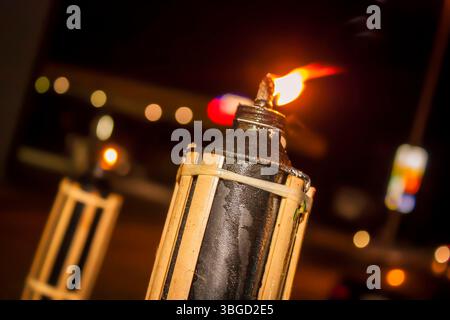 Lampe à huile traditionnelle pelita en bambou brûlant brillamment la nuit, créant une lueur chaude et atmosphérique sur un fond flou Banque D'Images