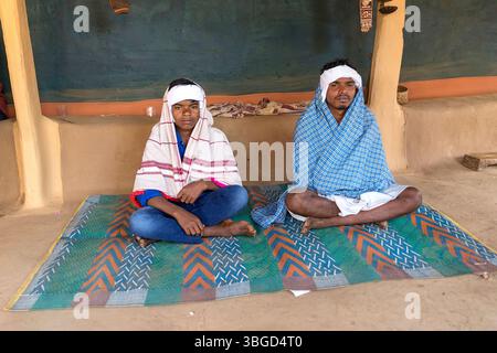 Groom et son frère cadet en vêtements traditionnels attendant le début d'une cérémonie de mariage, assis devant une maison de boue dans l'orissa en inde Banque D'Images