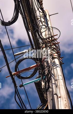 Bayahibe, République dominicaine 1er janvier 2025 : enchevêtrement de fils électriques et de communication créant un désordre chaotique sur le poteau d'alimentation électrique contre le ciel bleu Banque D'Images