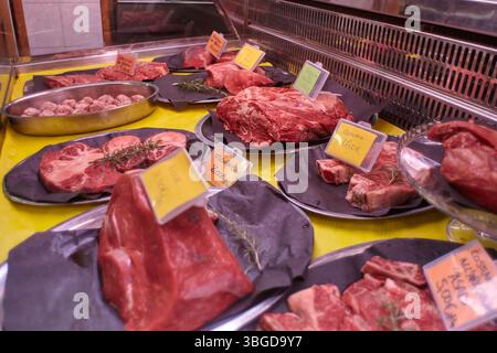Milan, Italie 1er janvier 2025 : coupes fraîches de bœuf et boulettes de viande assaisonnées de brins de romarin, exposées sur un comptoir réfrigéré, prêtes à la vente en A. Banque D'Images