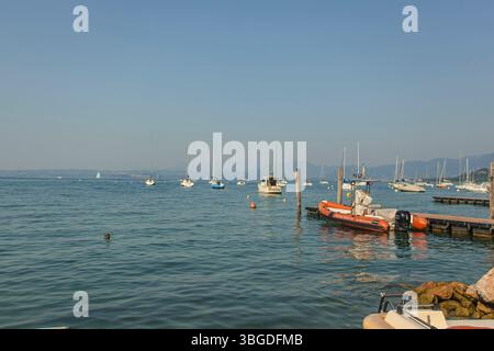 Lac de Garde, Italie 3 janvier 2025 : voiliers et bateaux à moteur flottent sur le lac de garde, près de bardolino et lazise, en italie, par une journée d'été ensoleillée Banque D'Images