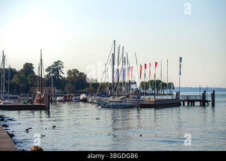 Lac de Garde, Italie 3 janvier 2025 : voiliers et yachts accostent à un quai sur le lac de garde, italie, avec des drapeaux colorés agitant dans la brise Banque D'Images