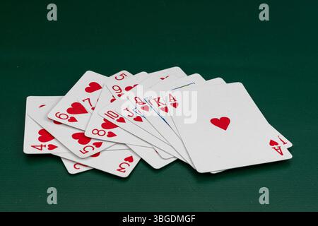 Cartes à jouer coeur dispersé sur la table de poker avec fond vert Banque D'Images