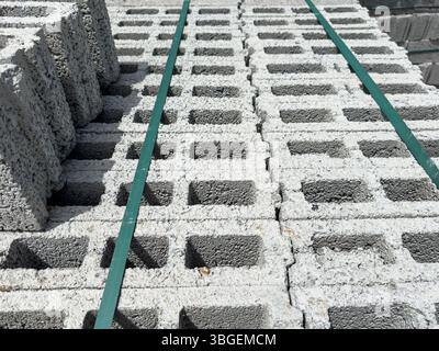 Blocs de béton cellulaire empilés vus d'un angle avec des sangles vertes pour la fixation. Convient pour la construction, les milieux industriels et la conception. Banque D'Images