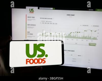 Stuttgart, Allemagne - 01 31 2025 : personne tenant un smartphone avec le logo de la société de restauration US Foods Holding Corp. sur l'écran devant le site Web. Banque D'Images