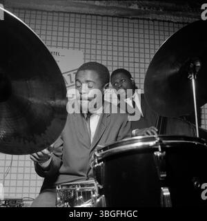 Der US-amerikanische Jazzschlagzeuger Buster Smith (vorn am Schlagzeug) und der bassiste George Joyner (im Hintergrund) BEI einem mitreißenden Live-Konzert in einem Club der 1960er Jahre. Beide Musiker sind im moment des Spiels vertieft, die Energie des Jazz ist spürbar. Banque D'Images