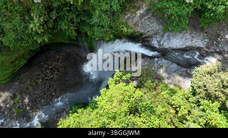 La perspective aérienne de la cascade de Tiu Kelep montre la rivière se faufilant à travers les rochers avant de tomber dans une piscine brumeuse cachée dans la verdure. Banque D'Images