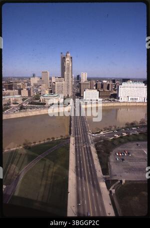 Une vue aérienne vers l'est au-dessus de la rivière Scioto vers le centre-ville de Columbus en 1981. Broad Street traverse la scène. Les bâtiments clés le long de la rivière comprennent Columbus City Hall, 90 West Broad Street, le bâtiment du Département des Transports de l'Ohio, 25 South Front Street, le Department of State Building de l'Ohio au 65 South Front Street, et la Leveque Tower au 50 West Broad Street. Banque D'Images