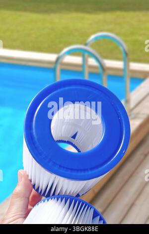 Cartouches filtrantes de piscine de remplacement dans la main d'une femme sur la toile de fond de la piscine. Traitement de l'eau, piscine à domicile, nettoyage, qualité de l'eau. Faible profondeur de champ Banque D'Images