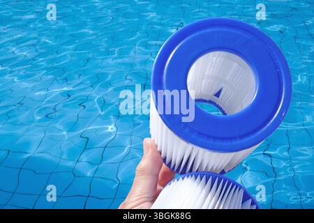 Cartouches filtrantes de piscine de remplacement dans la main d'une femme sur la toile de fond de la piscine. Traitement de l'eau, piscine à domicile, nettoyage, qualité de l'eau. Faible profondeur de champ Banque D'Images