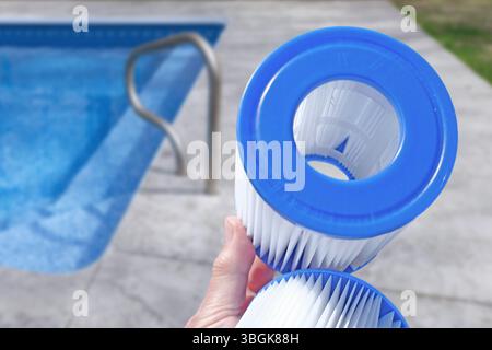 Cartouches filtrantes de piscine de remplacement dans la main d'une femme sur la toile de fond de la piscine. Traitement de l'eau, piscine à domicile, nettoyage, qualité de l'eau. Faible profondeur de champ Banque D'Images