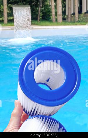Cartouches filtrantes de piscine de remplacement dans la main d'une femme sur la toile de fond de la piscine. Traitement de l'eau, piscine à domicile, nettoyage, qualité de l'eau. Faible profondeur de champ Banque D'Images