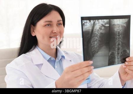Médecin souriant examinant l'IRM du cou en clinique Banque D'Images