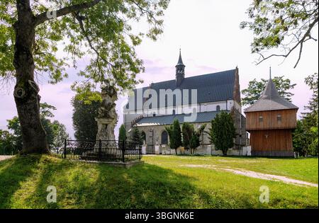 Église paroissiale gothique de Pierre et Paul (Kosciol pw. ss. Piotra i Pawla) et un clocher en bois autoportant à Beszowa dans la voïvodie de Swietokrzyskie en Pologne Banque D'Images