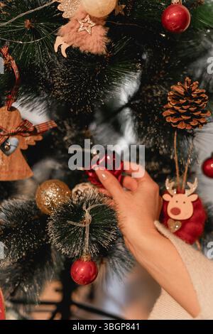 Deux générations se connectent en silence tandis que leurs mains se rencontrent sur des ornements dorés scintillants prêts à accrocher sur l'arbre soulignant l'intimité émotionnelle Banque D'Images