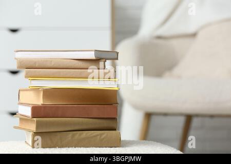 Pile de différents livres sur pouf dans la pièce claire Banque D'Images