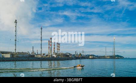 Balikpapan, Indonésie - 19 avril 2025. Le marchand navigue son bateau devant les vastes installations de la raffinerie de pétrole Pertamina à Balikpapan, dans la province de Banque D'Images