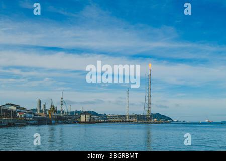 Balikpapan, Indonésie - 19 avril 2025. Une vue d'une raffinerie de pétrole le long de la côte à Balikpapan, Kalimantan oriental, Indonésie, avec l'horizon de la ville dedans Banque D'Images