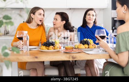 Des femmes heureuses se sont rassemblées autour d'une table festive ; participant à des discussions animées et appréciant les délices du vin Banque D'Images