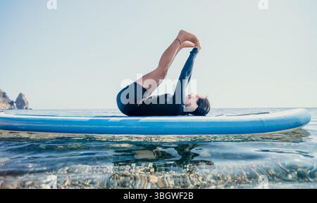 Yoga Paddleboard Ocean Man pratique le yoga pose sur Paddleboard dans Ocean Banque D'Images