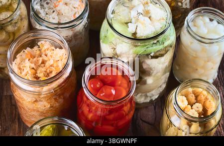Différents légumes conservés fermentés dans des bocaux en verre sur un fond en bois Banque D'Images